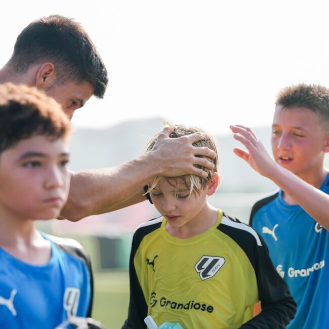 A coach of LaLiga Cademy Dubai congratulating his player after they defeated Ajax youth Academy Dubai in DOFA