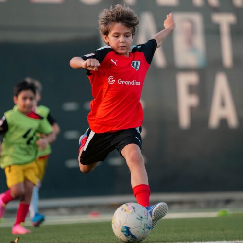 A young boy doing a football drill at a football training camps near you in Dubai Sports City